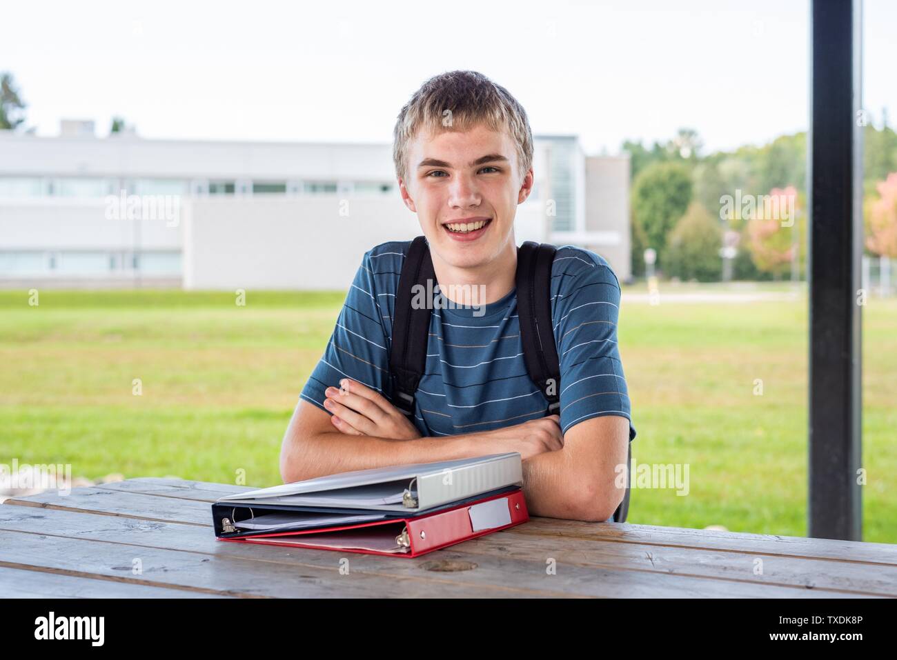 Happy Teenager seine Hausaufgaben im Freien tun neben einer Schule. Stockfoto