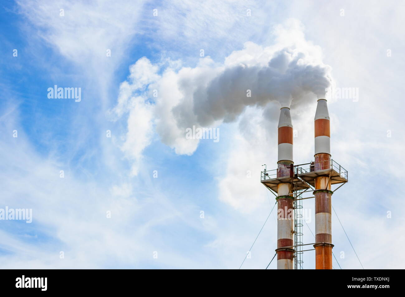 Schließen Sie herauf Bild von zwei Schornsteinen waberndem Rauch in die Atmosphäre gegen den blauen Himmel mit Kopie Raum Stockfoto
