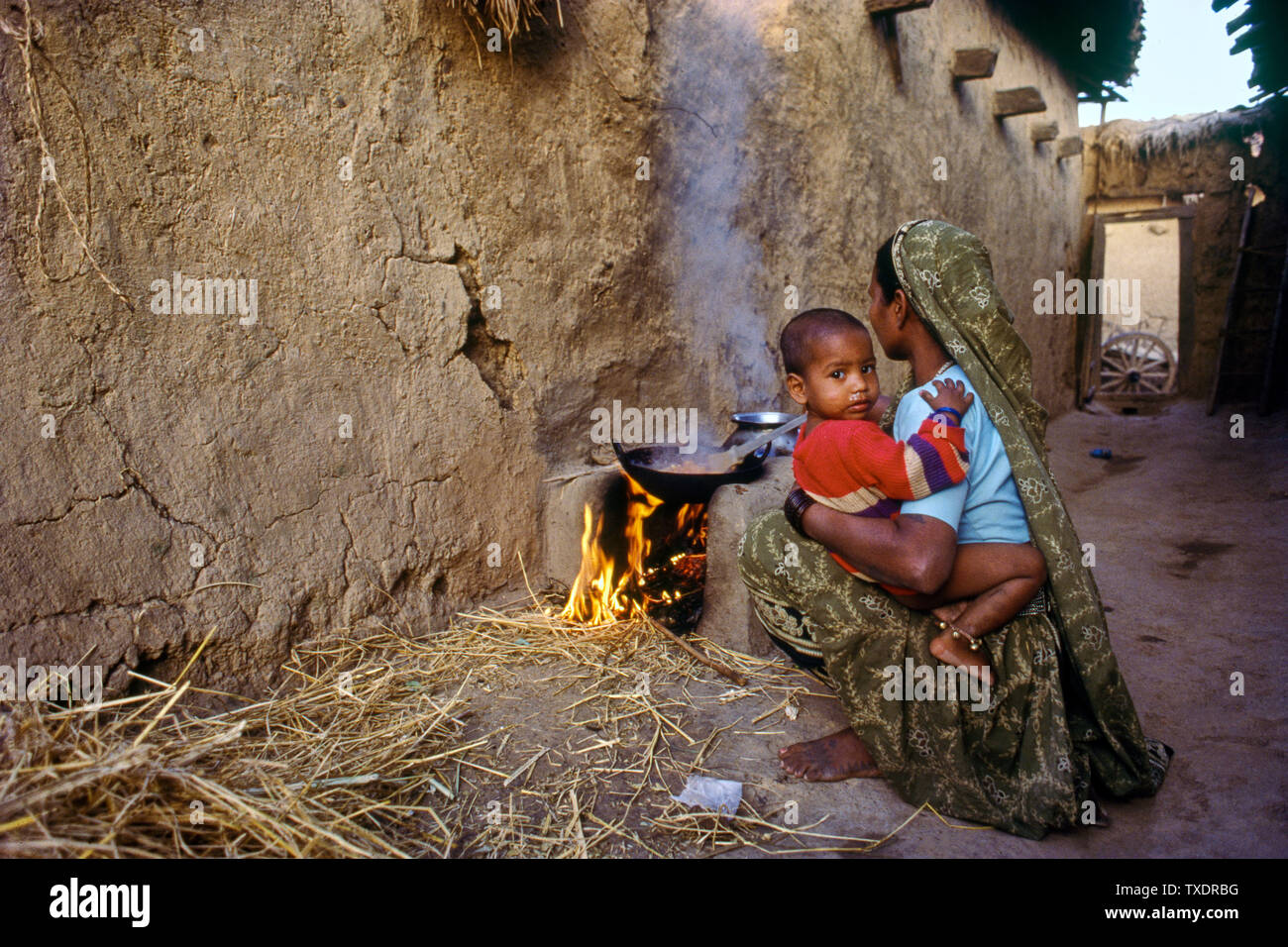 Frau mit Kind im Schoß kochen auf traditionellen Herd, Gujarat, Indien, Asien Stockfoto