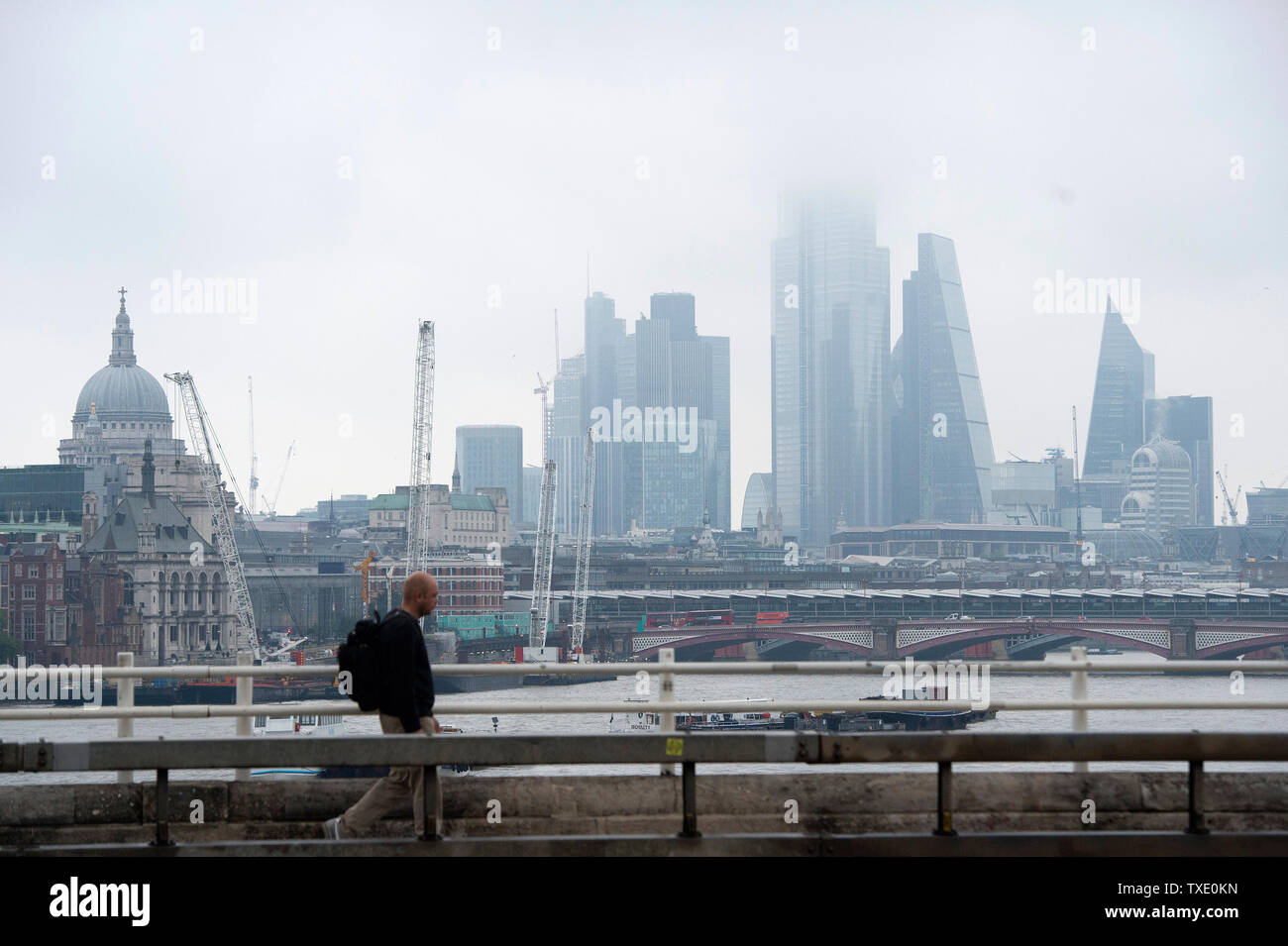 Ein Mann auf der Waterloo Bridge in London. Gewitter durch eine Feder des warmen kontinentalen Luft angetrieben haben begonnen zu entladen' kräftige Regengüsse und Blitze über South East England. Stockfoto