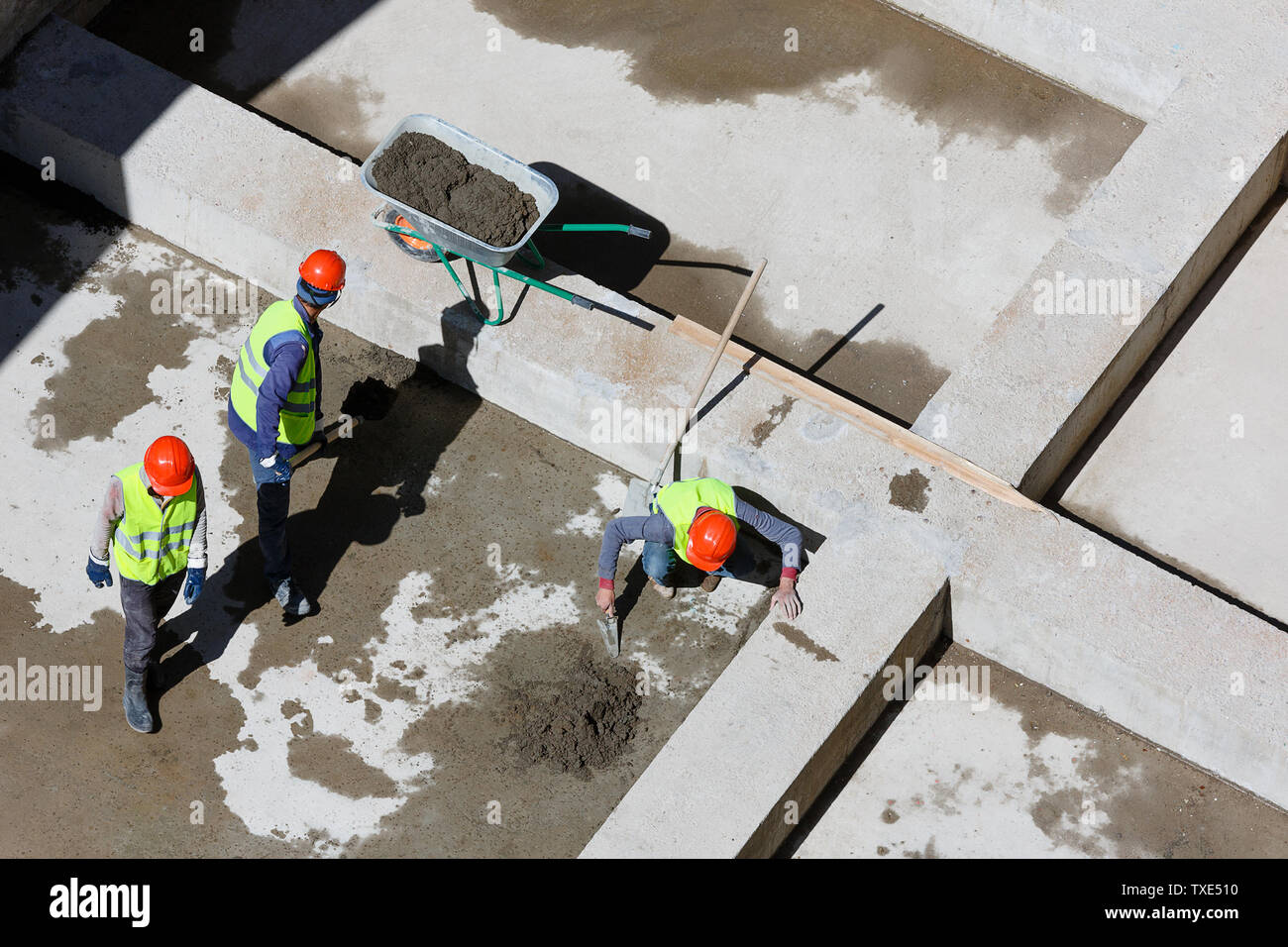Uniformierte Mitarbeiter sauberen Sand auf einer Baustelle, Ansicht von oben. Stockfoto