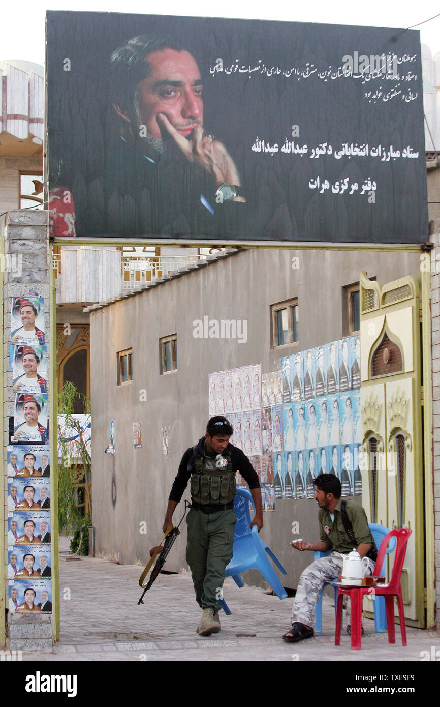 Security Guards sitzen unter einem großen Banner der Präsidentschaftskandidaten und ehemalige Außenminister Abdullah Abdullah bei seiner Kampagne Mitte in Herat, Afghanistan am 13. August 2009. Die afghanischen Präsidentschaftswahlen werden am 20. August statt. UPI/Mohammad Kheirkhah Stockfoto