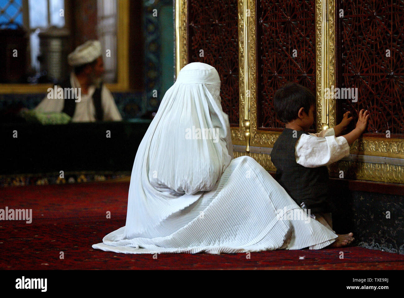 Eine weiße Burka bekleideten Frau und ihr Sohn betet, innerhalb der Blauen Moschee in Mazar-e-Sharif (Grab des Erhabenen), Afghanistan in der Provinz Balkh am 24. August 2009. Während des Monats Ramadan, dem neunten Monat des islamischen Kalenders, Muslime verzichten auf das Essen, Trinken und Rauchen von Sonnenaufgang bis Sonnenuntergang. Mazar-e-Sharif ist die viertgrößte Stadt des Landes und liegt an der Nordküste entfernt. UPI/Mohammad Kheirkhah Stockfoto