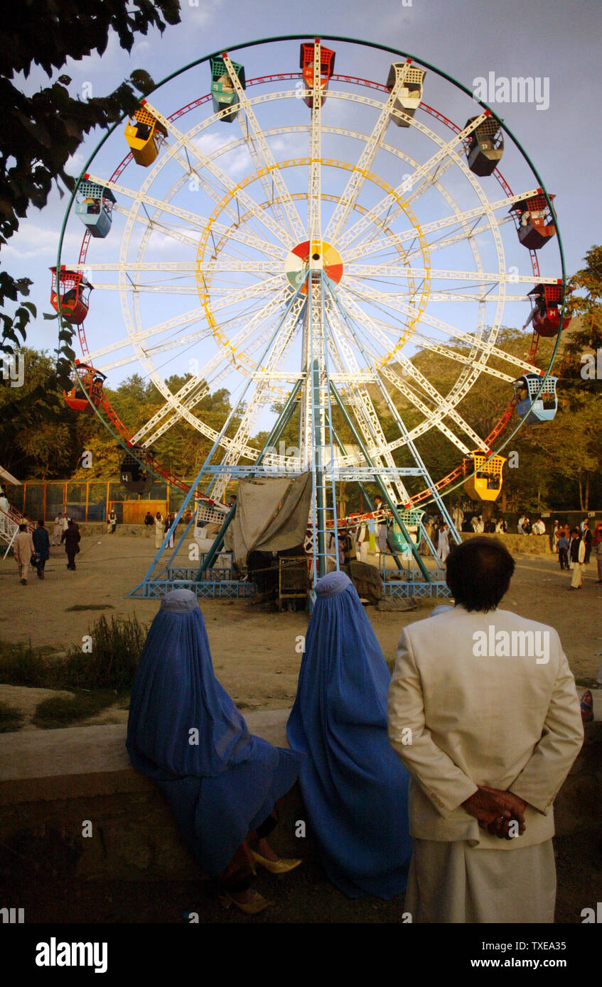 Ein Mann und zwei Burka gekleidete Frauen sehen Sie ein Riesenrad gehen um, da sie den Eid Al-Fitr, den Feiertag markiert das Ende der muslimischen heiligen Fastenmonats Ramadan in Kabul, Afghanistan am 21. September 2009 feiern. UPI/Mohammad Kheirkhah Stockfoto