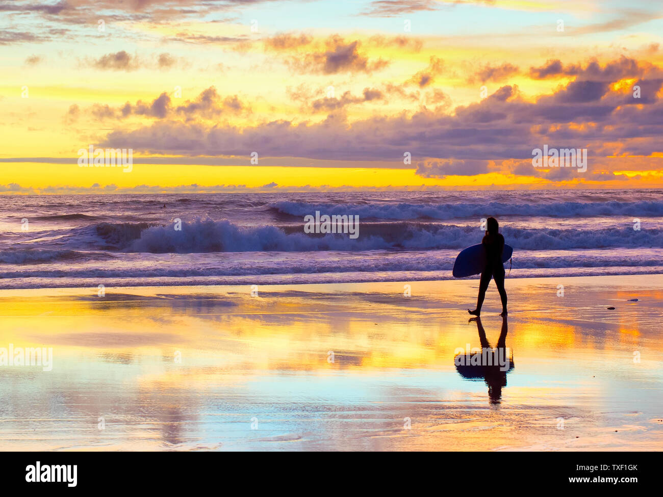Surfer gehen am Strand mit Surfbrett bei Sonnenuntergang. Bali, Indonesien Stockfoto