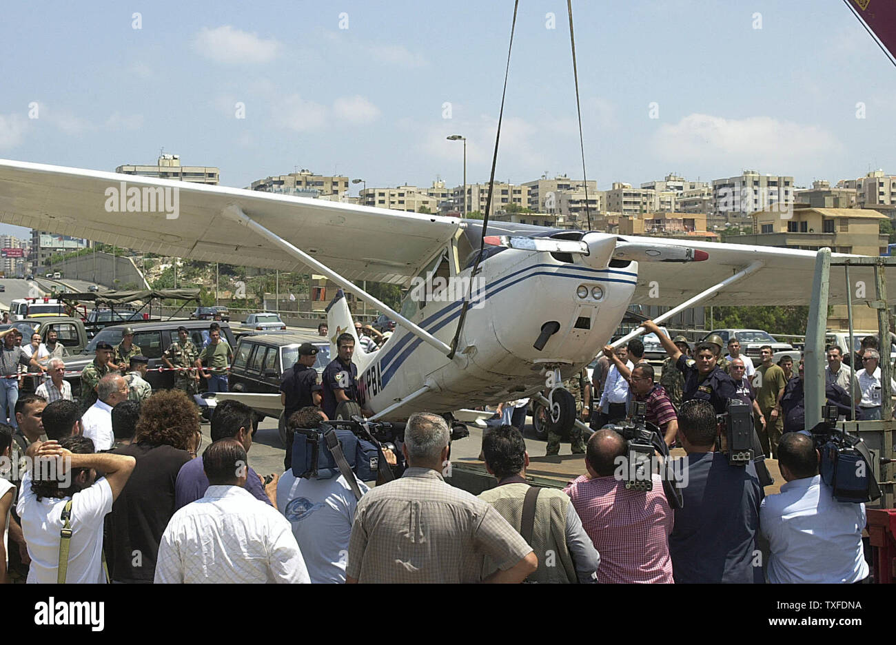 Menschen versammeln sich in einem kleinen Flugzeug, das auf einer vielbefahrenen Autobahn in Beirut am 3. Juli 2004 gelandet, nachdem technische Probleme. Nach Angaben von Zeugen, der Pilot hatte die Anwesenheit des Geistes seinen Kopf aus dem Fenster zu halten und zu kreischen an der Verkehr stoppt, Unfälle zu vermeiden (UPI Foto/Mohammed Tawil) Stockfoto