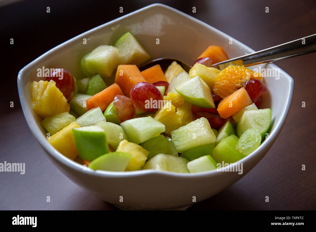 Große weiße Schüssel gesunder frischer Obstsalat mit Trauben, Melone, Orange, Ananas und Apfel Stockfoto