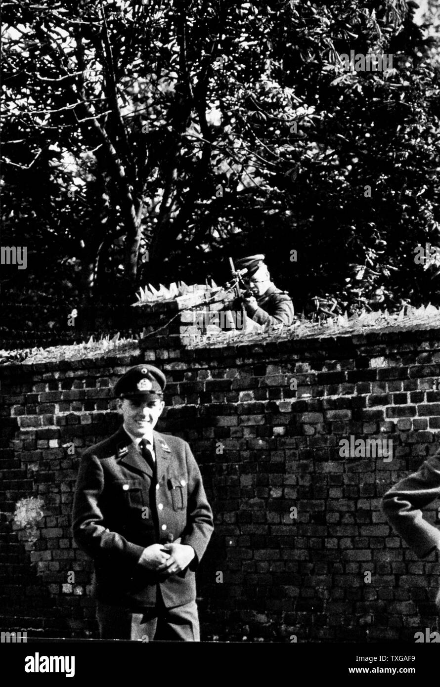 Berliner Mauer. West-Berliner in Uniform vor der Berliner Mauer, Soldat zeigenden Waffe über Mauer. Stockfoto
