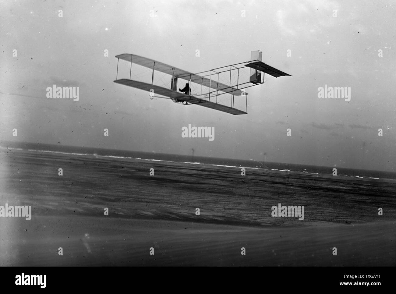 Linken hinteren Dreiviertelansicht der Gleitschirm im Flug in Kitty Hawk, North Carolina. Orville, begleitet von seinem Bruder Lorin, seinem Neffen Horace und seinem Freund Alexander Ogilvie, von England, kam zur Durchführung von gleiten Experimente mit einem Segelflugzeug Wright 1911 angetriebene Maschine ähnlich aber es mangelt an seinem Motor... Stockfoto