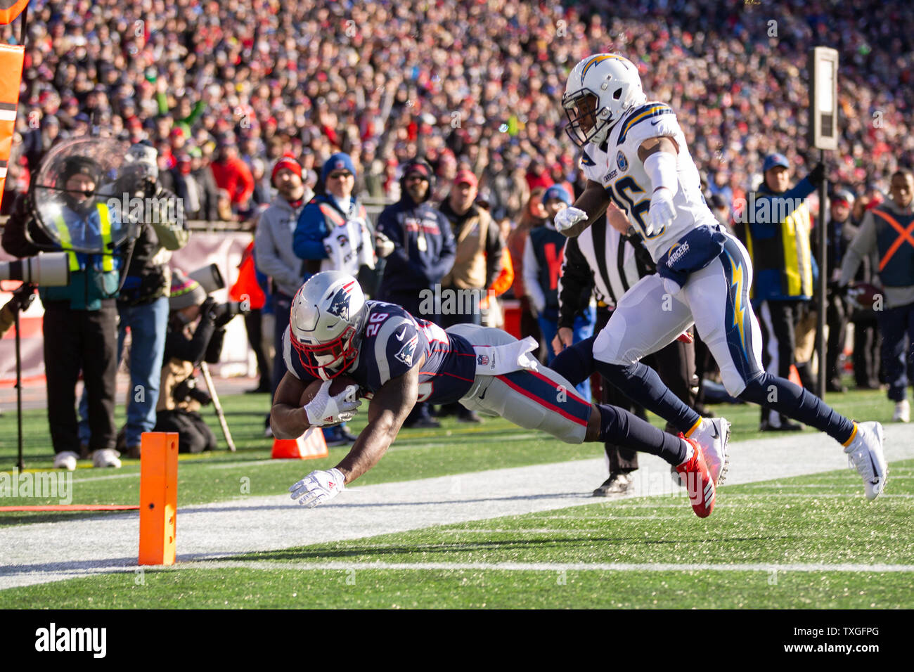 New England Patriots zurück laufen Sony Michel (26) taucht in die End Zone, während durch jagte Los Angeles Ladegeräte cornerback Casey Hayward Jr. basierend auf einem 14-Yard-tragen im ersten Quartal des AFC Teilungsendspielspiel am Gillette Stadium in Foxborough, Massachusetts am 13. Januar 2019. Die Patrioten besiegten die Ladegeräte 41-28. Foto von Matthew Healey/UPI Stockfoto