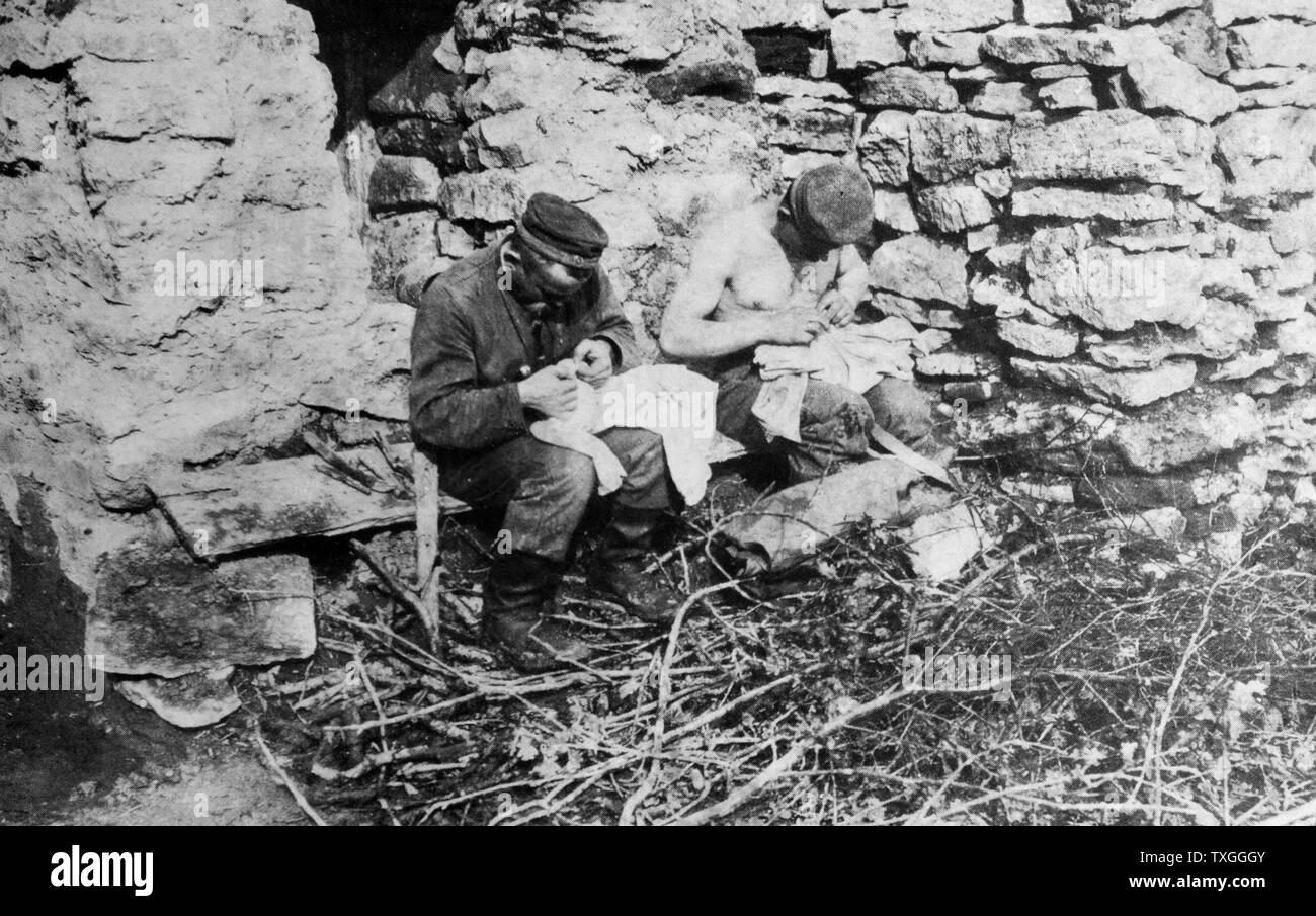 Foto von deutschen Soldaten auf der Jagd nach Läuse auf ihrer Kleidung in den Schützengräben. Datiert 1914 Stockfoto