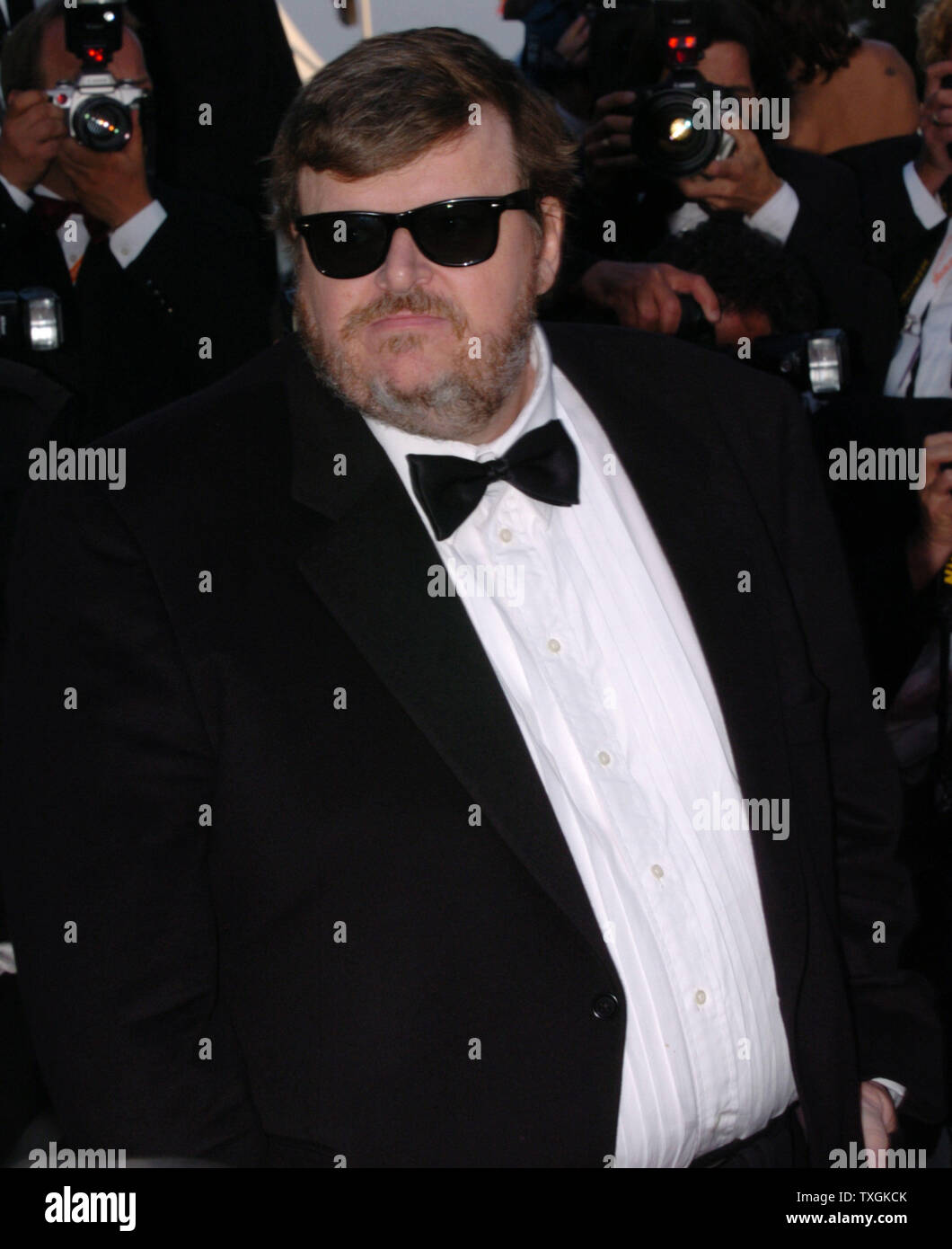 Regisseur Michael Moore stellt für die Paparazzi auf dem roten Teppich vor der Galavorstellung von "Bad Santa" im Palais des Festivals 19. Mai 2004 während der Filmfestspiele von Cannes in Cannes, Frankreich. Moore's Film 'Fahrenheit 911'', im Wettbewerb um die Palme d'Or, Anfang dieser Woche aussortiert wurde und mit einer lang anhaltenden Applaus vom Publikum. (UPI Foto/Christine Kauen) Stockfoto