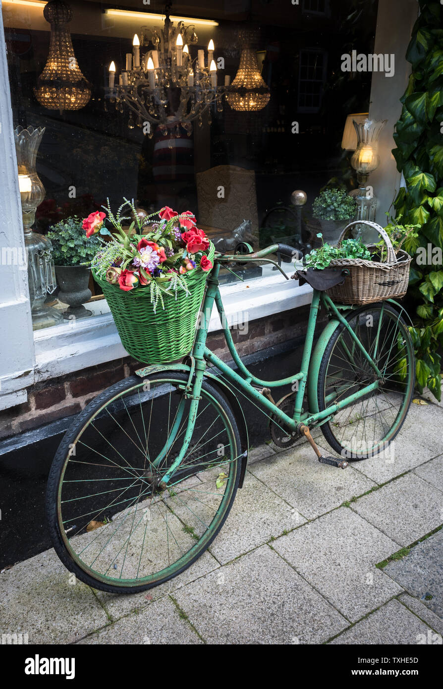 Eine alte vintage Bike angezeigte Blumenkörbe außerhalb ein Antiquitätengeschäft in Großbritannien. Stockfoto