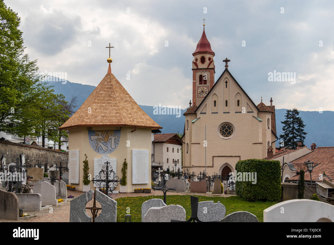 Panorama der Kirche, die Pfarrkirche St. Johannes der Taufer, mit Friedhof und Kapelle in der Gemeinde Dorf Tirol. Tirol, Südtirol, Italien Stockfoto