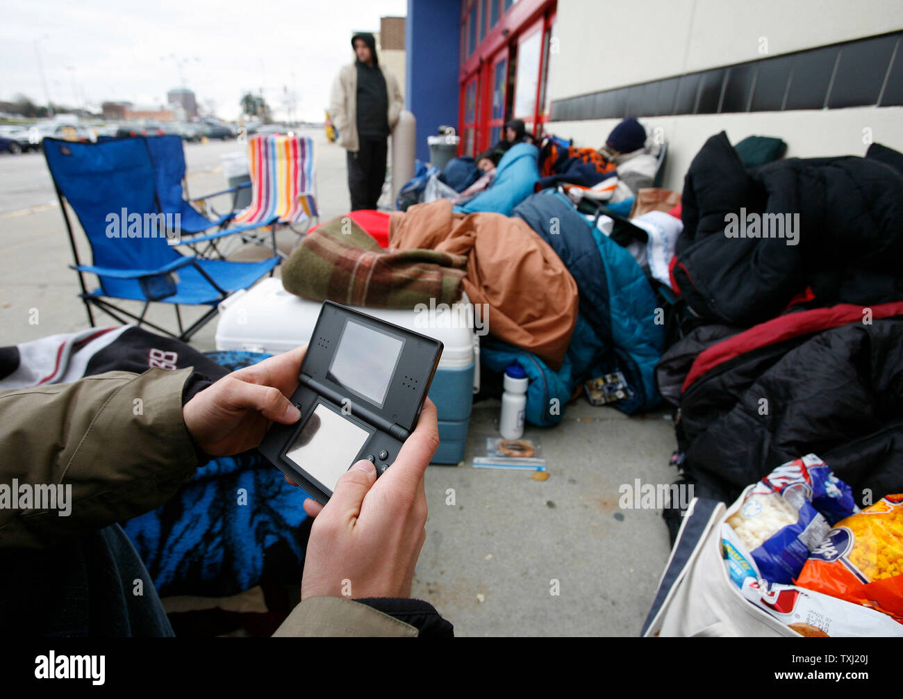 Ein Kunde spielt eine Nintendo DS tragbare Video Spiel während der Wartezeit die neue Sony PlayStation 3 Video Game System außerhalb einer besten Stores in Downers Grove, Illinois kaufen am 16. November 2006 zu erwerben. Die Vorrichtung, die einzelverkäufe Für entweder $ 500 oder 600 $, je nach Modell, geht auf Verkauf in ausgewählten Städten bundesweit um Mitternacht am 17. November. (UPI Foto/Brian Kersey) Stockfoto