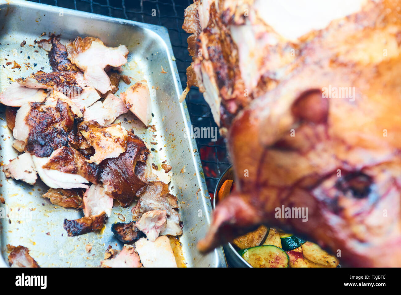 Chef Hände Schneiden ganze gegrillte Schweinefleisch für Steaks mit Messer. Vom Schwein gegrillte traditionelle Kohle und Feuer. Das kleine Schwein wird ganz auf einem offenen Feuer geröstet. P Stockfoto