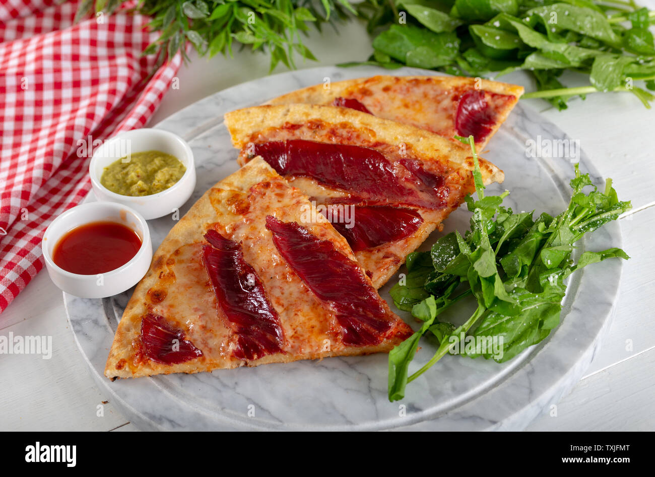 Geräucherten Rippchen Pizza mit Rucola und Parmesan auf Holz Tisch Hintergrund. Stockfoto