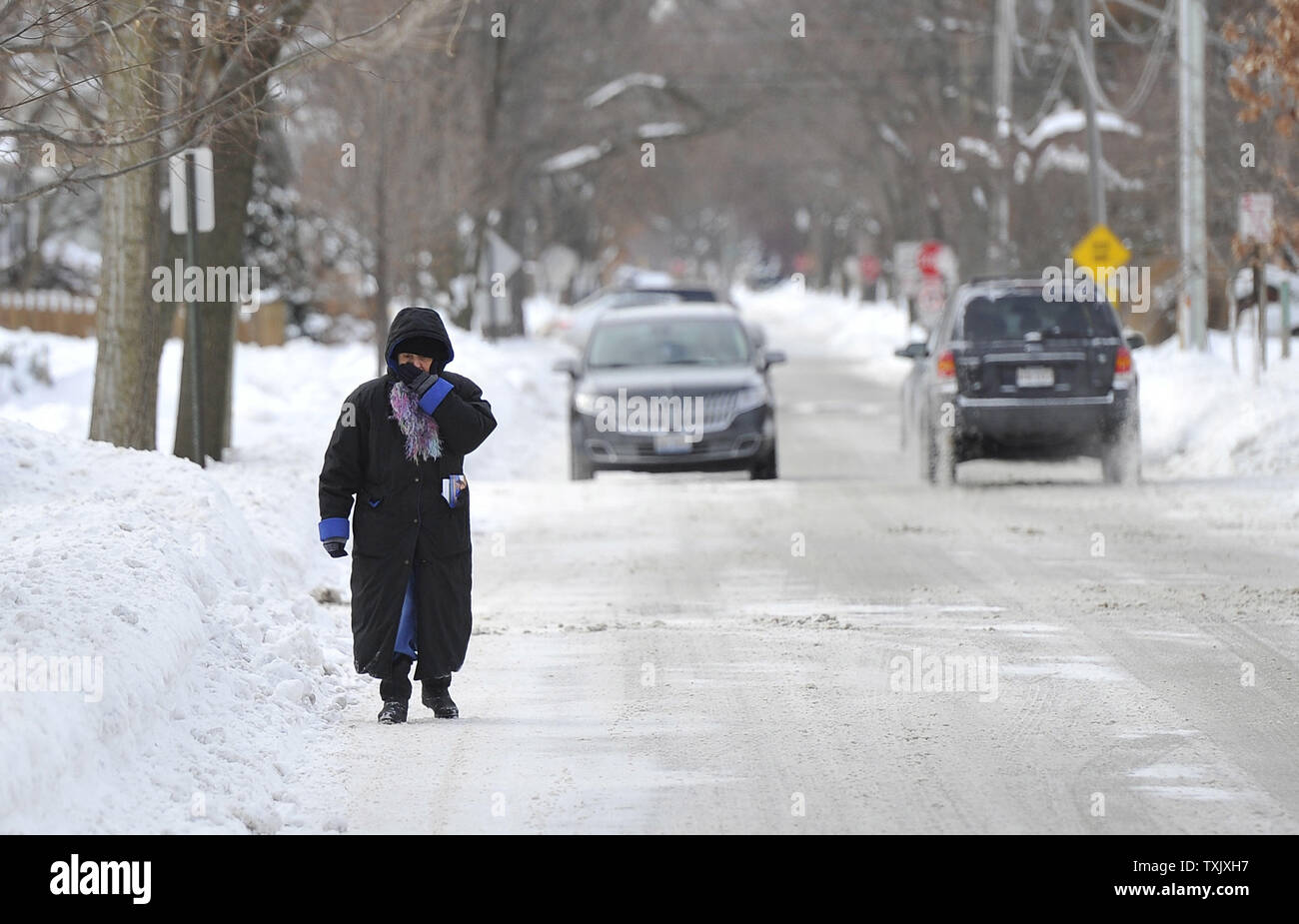 Eine Frau deckt ihr Gesicht, als sie in die Straße Wanderungen durch Schnee im Chicagoer Vorort Park Ridge, Illinois stapfen am 7. Januar 2014 zu vermeiden. Chicago erlebt seinen zweiten Tag der minusgraden als arktische Luft masse setzte die Region griff zu. UPI/Brian Kersey Stockfoto