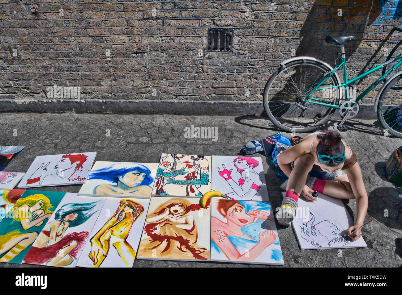 Junge Künstler zeichnen und Verkauf von Gemälden in der Straße Brick Lane Sonntag Markt London England Großbritannien UK Stockfoto