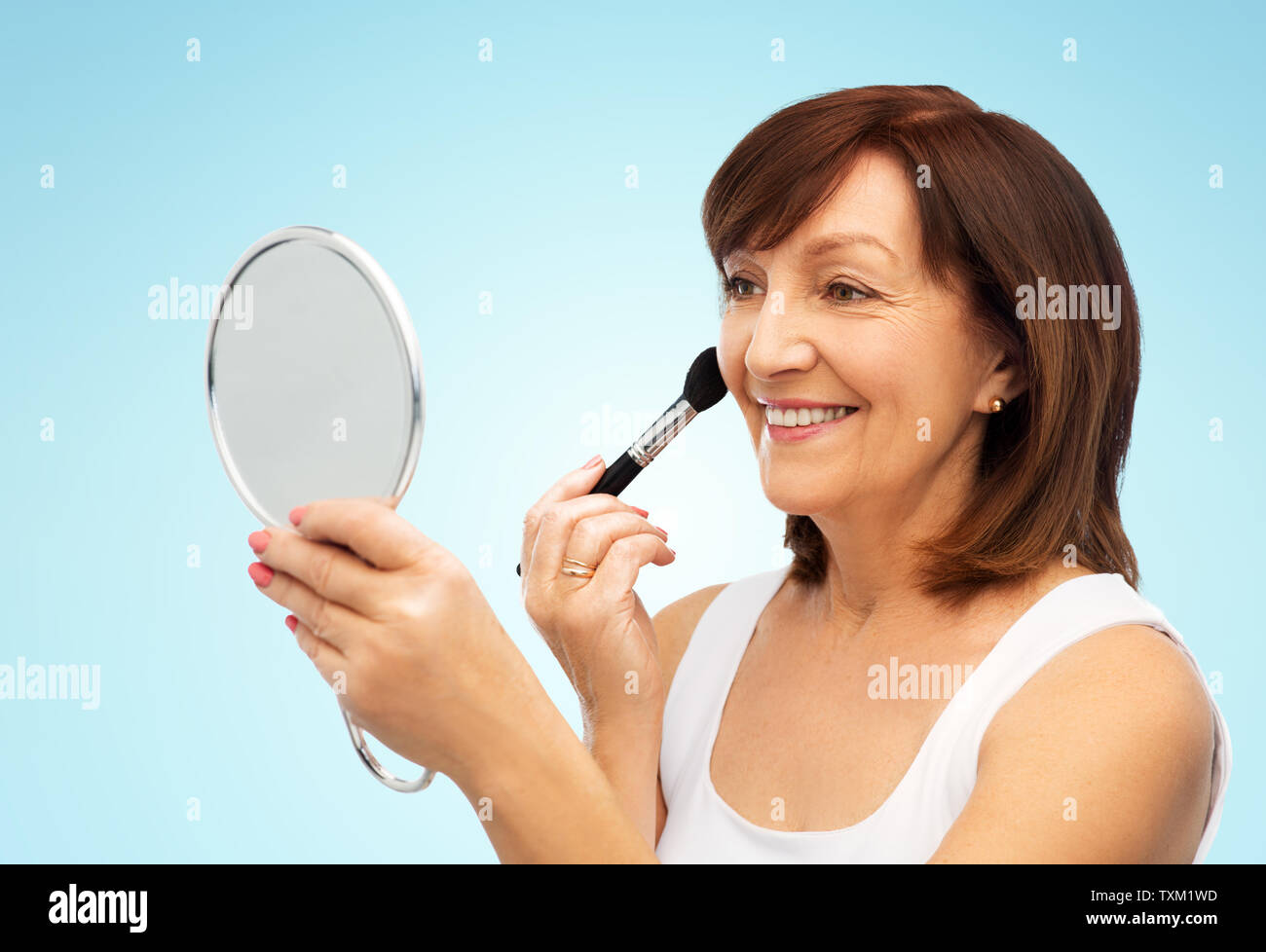 Ältere Frau mit Spiegel und Make up Blush Pinsel Stockfoto
