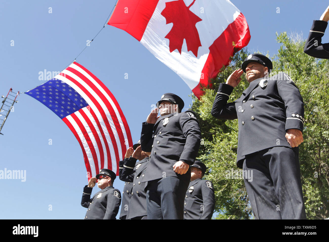 Die Feuerwehrleute aus der Denver Feuerwehr salute beim Stehen auf ihren Geräten unter übergroße amerikanische und kanadische Flaggen während der Internationale Verband der Feuerwehrleute jährliche Gefallen Fire Fighter Gedenkfeier in Colorado Springs am 19. September 2015. Fast 300 Namen der Feuerwehrleute, die in der Linie der Aufgabe innerhalb des letzten Jahres gestorben sind, wurden gelesen. Foto von Bill Greenblatt/UPI Stockfoto