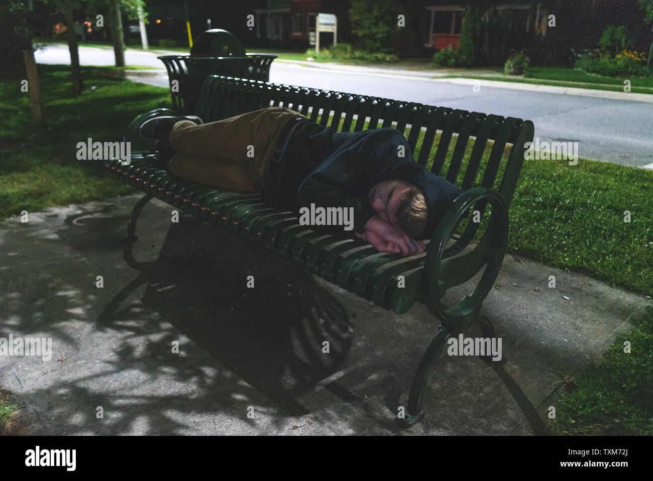 Obdachlose jugendlich liegend auf einer Parkbank. Stockfoto