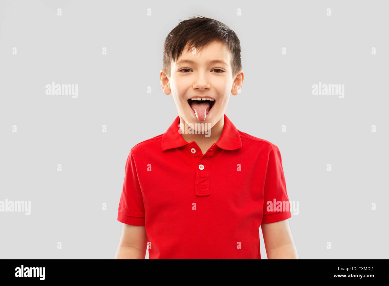 Junge in rot Polo T-Shirt seine Zunge angezeigt Stockfoto