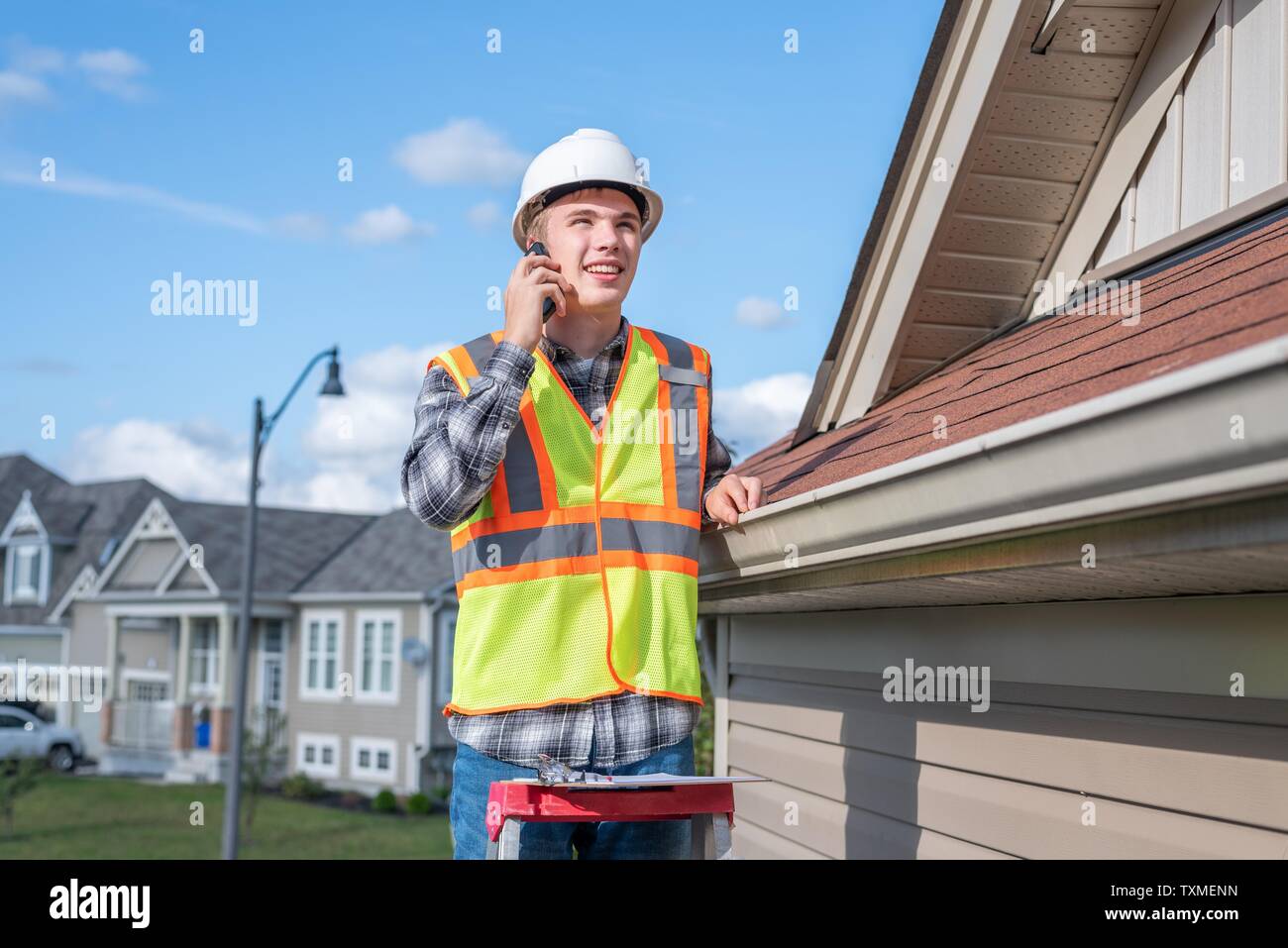 Der junge Architekt stand auf einer Leiter und über sein Handy. Stockfoto
