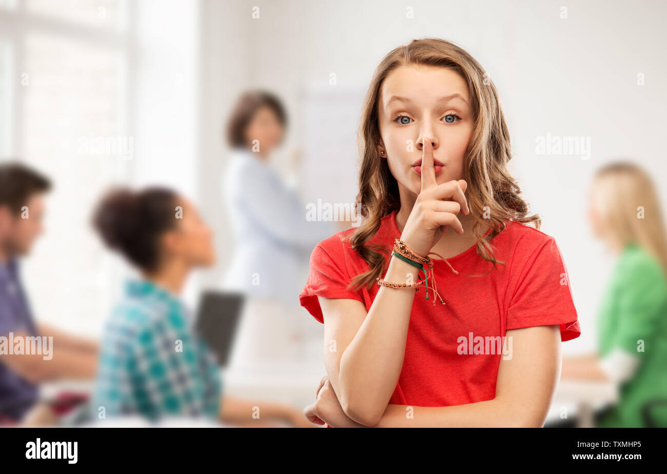 Teenage Mädchen im roten T-Shirt mit dem Finger auf den Lippen Stockfoto