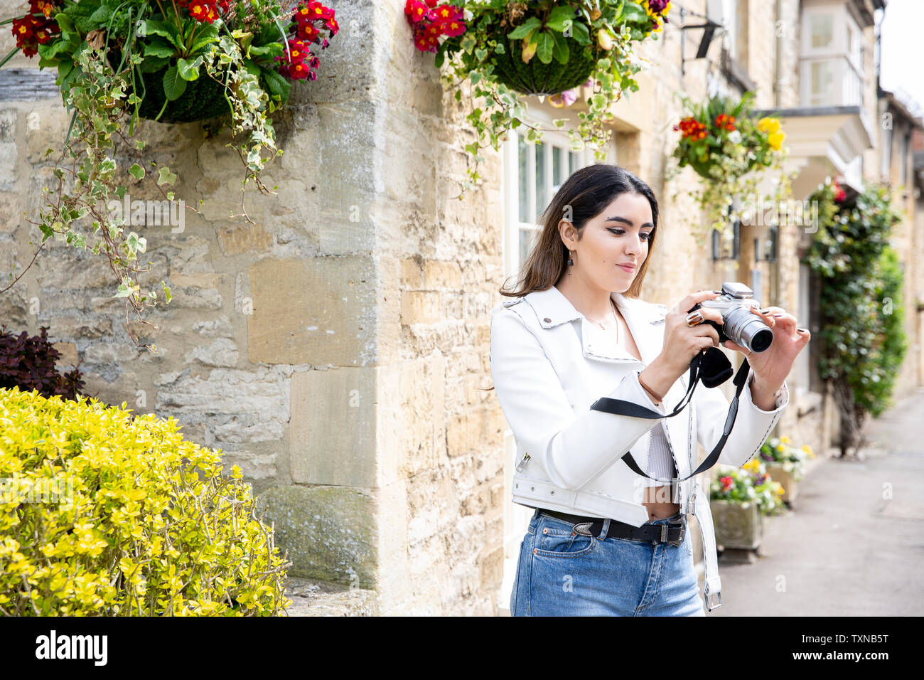 Junge Frau auf Dorf Straße überprüfung Fotos Digitalkamera, Cotswolds, England Stockfoto