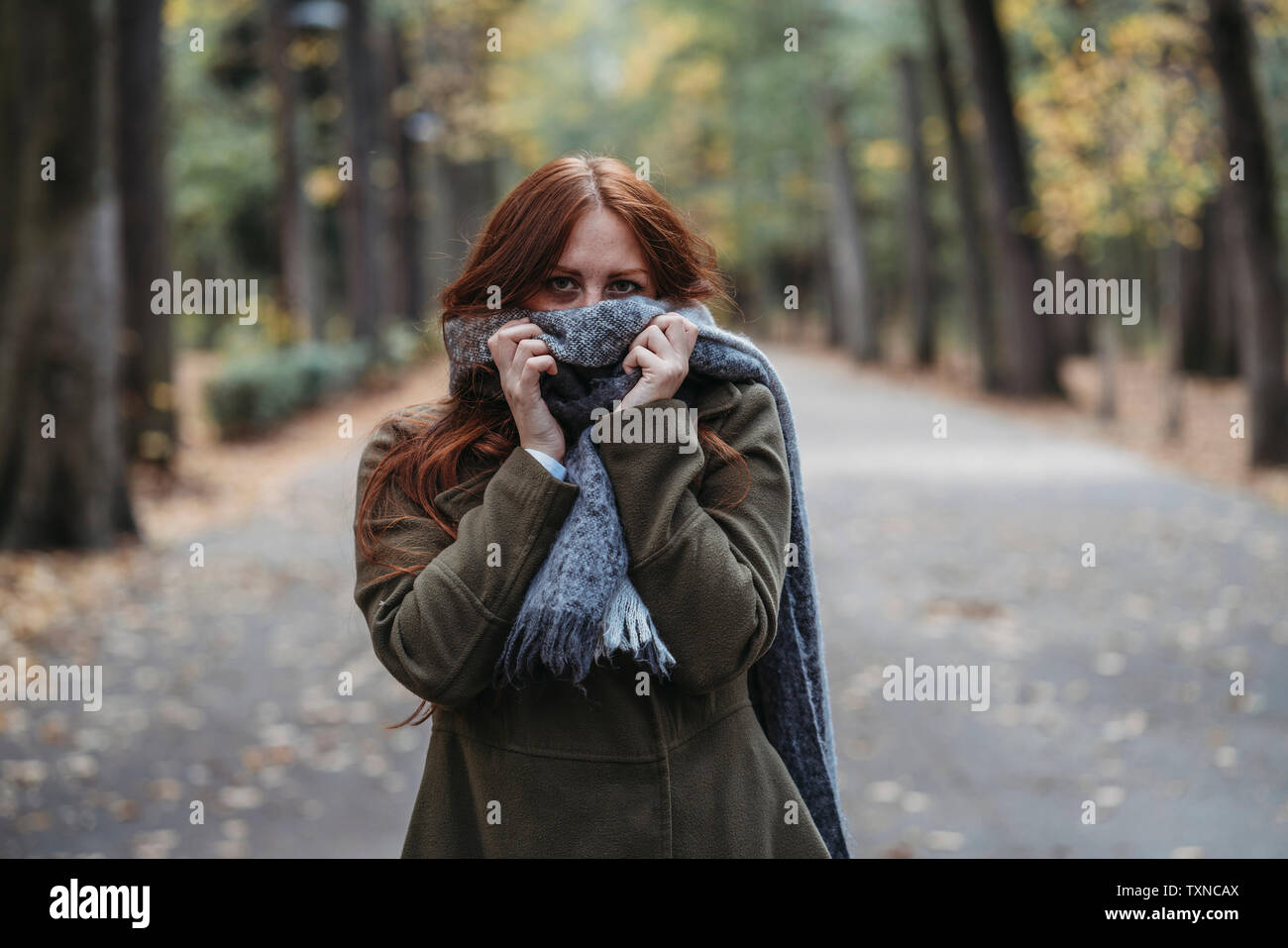 Junge Frau mit langen roten Haaren im Herbst park Mund mit Schal, Porträt Stockfoto