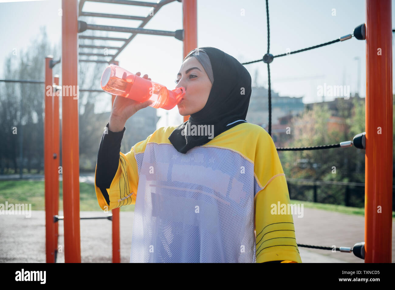 Calisthenics Klasse im Fitnessbereich im Freien, junge Frau trinkt aus der Flasche Wasser Stockfoto