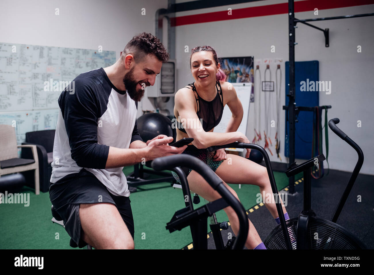 Junge Frau und Mann training zusammen auf gym Heimtrainer, an Smartphone suchen Stockfoto