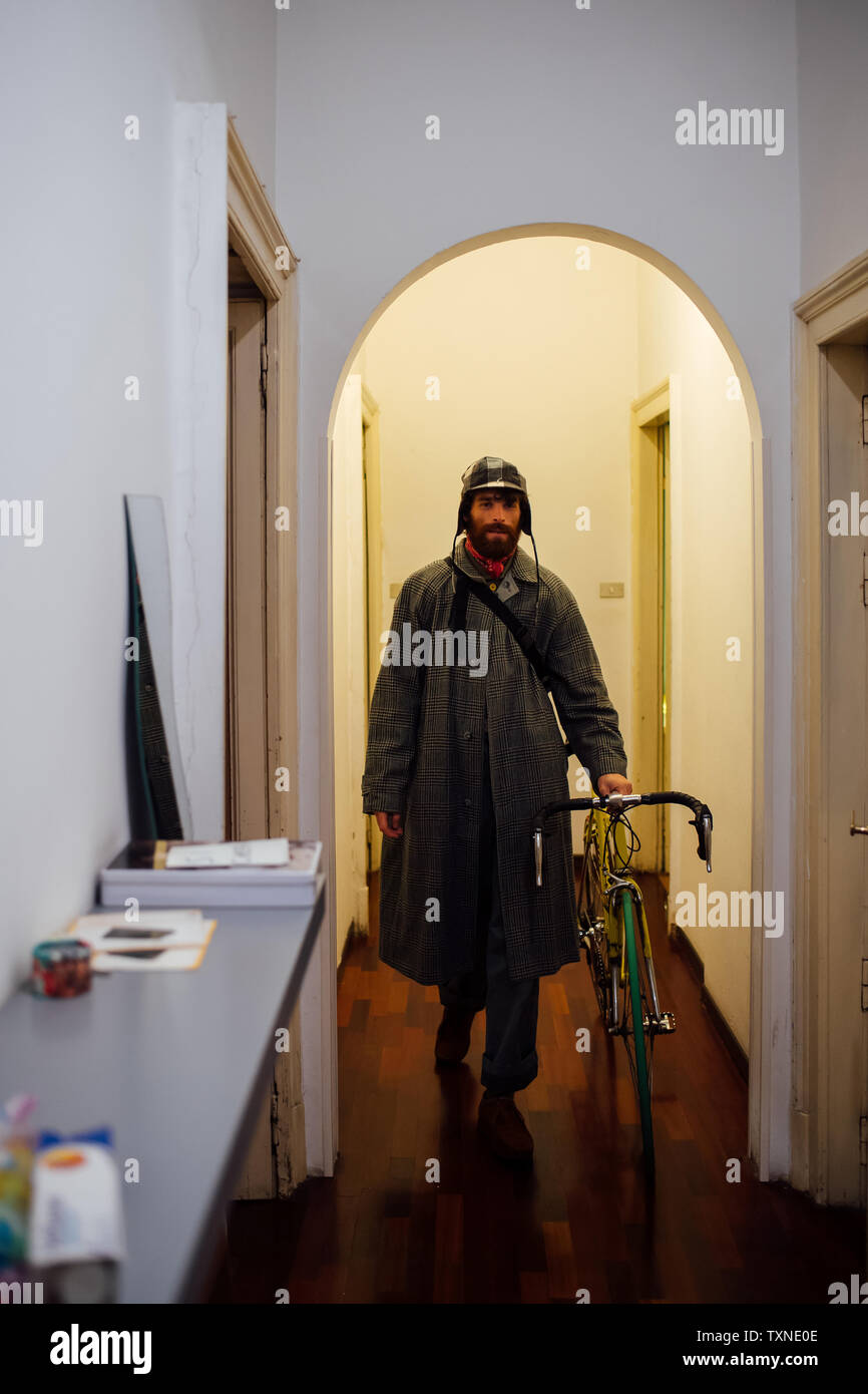 Bärtiger junger Mann Verlassen der Wohnung mit Fahrrad Stockfoto