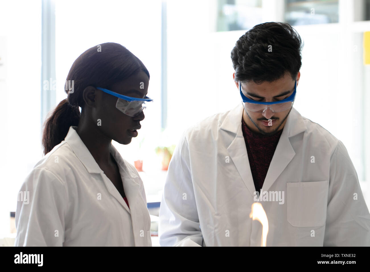Jungen Wissenschaftlern und Wissenschaftlerinnen mit Bunsenbrenner im Labor experimentieren Stockfoto