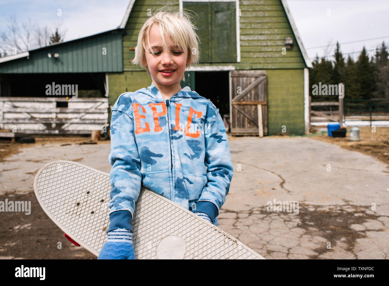 Blonde Junge mit Skateboard in Hof, Porträt Stockfoto