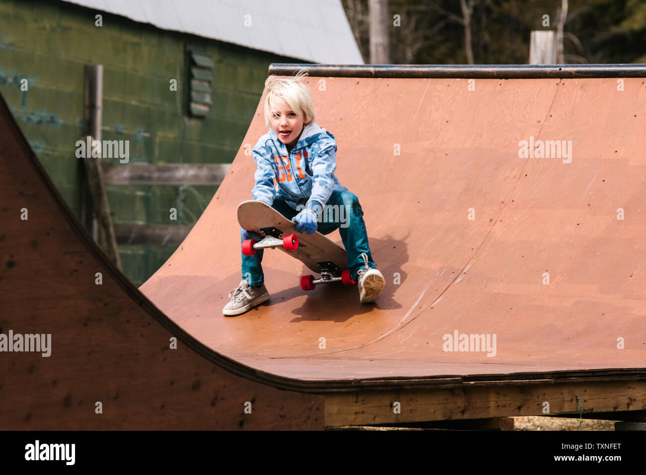 Junge Vorbereitung auf Skateboard auf hölzernen Skateboard Rampe zu sitzen Stockfoto