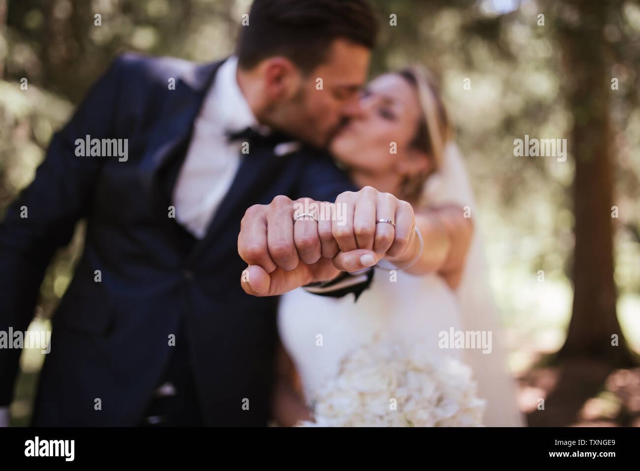 Romantische Braut und Bräutigam küssen und Anzeigen Trauringe in Wäldern, selektiven Fokus auf Händen Stockfoto