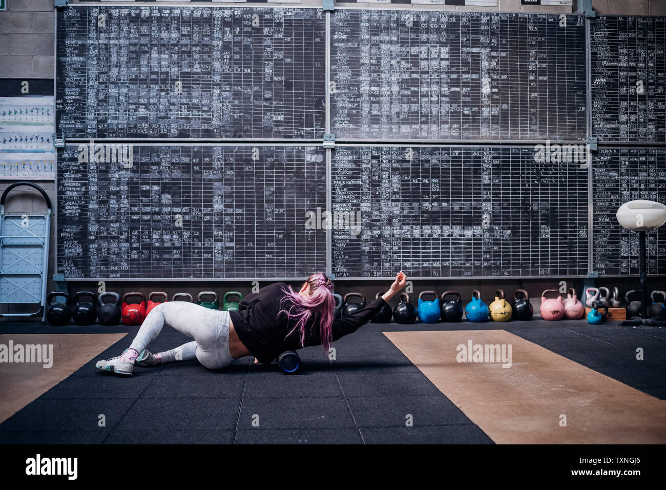 Junge Frau massiert Körper mit schaumstoffrolle in der Turnhalle Stockfoto