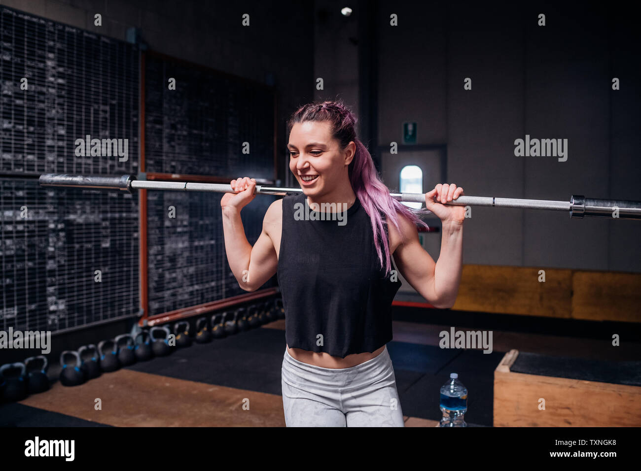 Junge Frau heben Gewicht bar in der Turnhalle Stockfoto