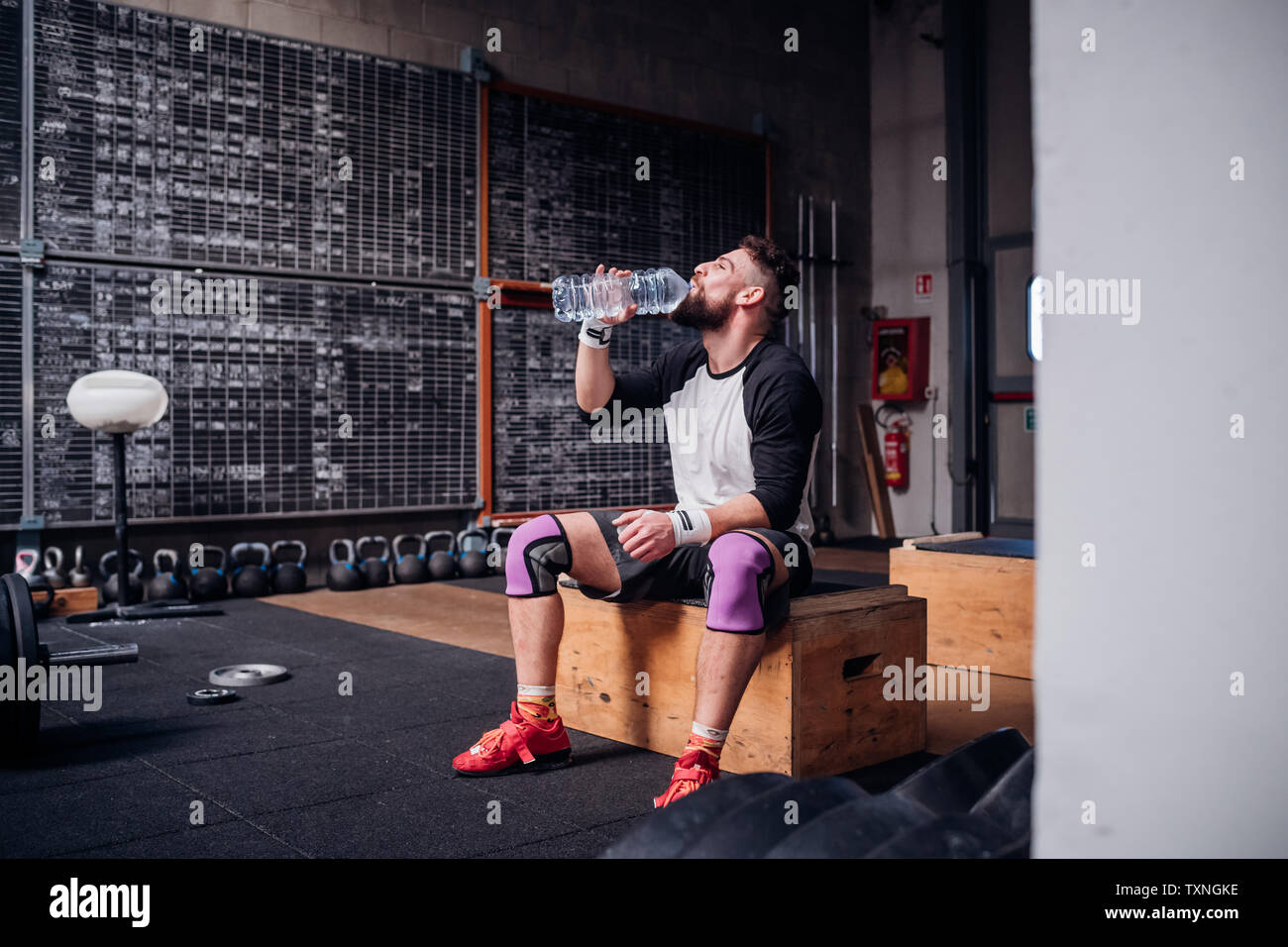 Junger Mann Trinkwasser im Fitness-Studio Stockfoto