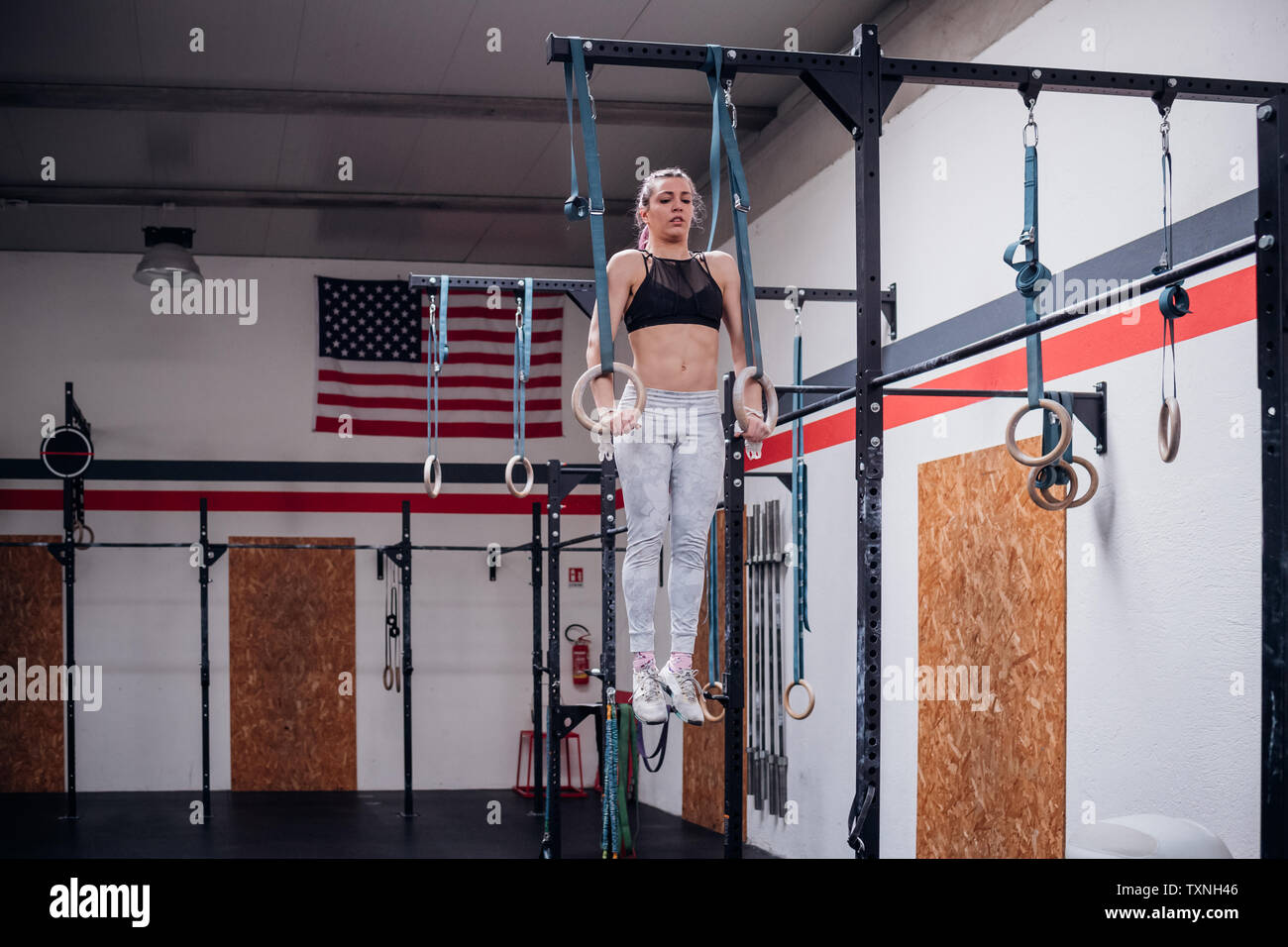 Junge Frau Balancieren auf Gymnastik Ringe in der Turnhalle Stockfoto