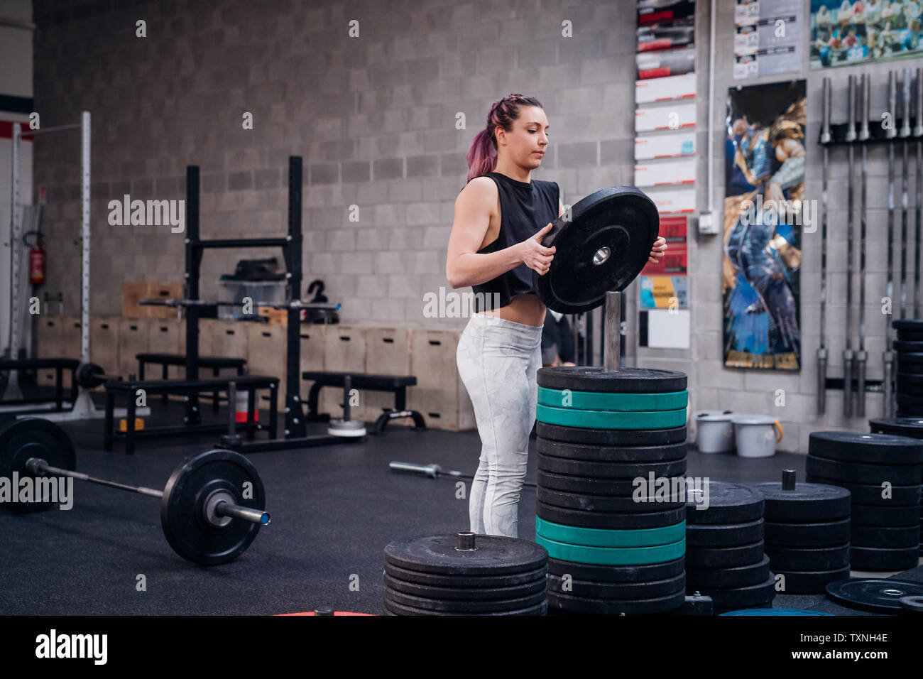 Junge Frau das Gewicht der Platte auf Rack in der Turnhalle Stockfoto