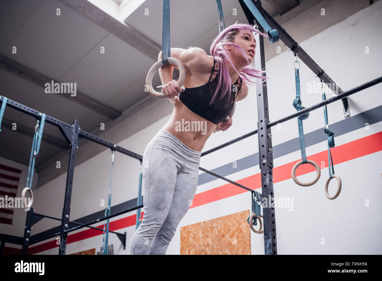 Junge Frau Balancieren auf Gymnastik Ringe in der Turnhalle Stockfoto