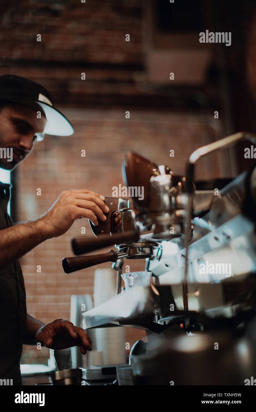 Barista mit Kaffeemaschine im Cafe, flacher Fokus Seitenansicht Stockfoto