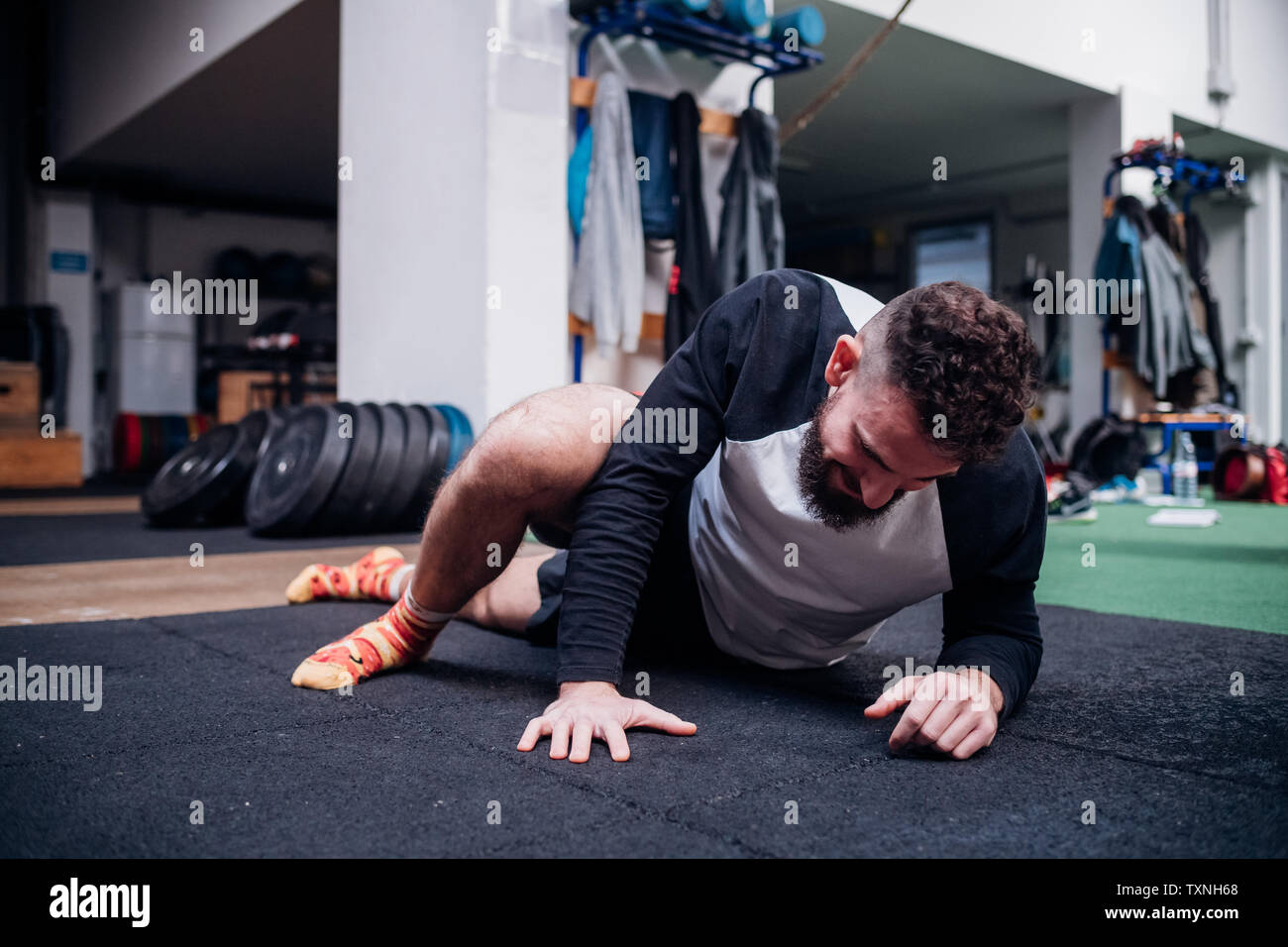 Junger Mann stretching Beine in der Turnhalle Stockfoto