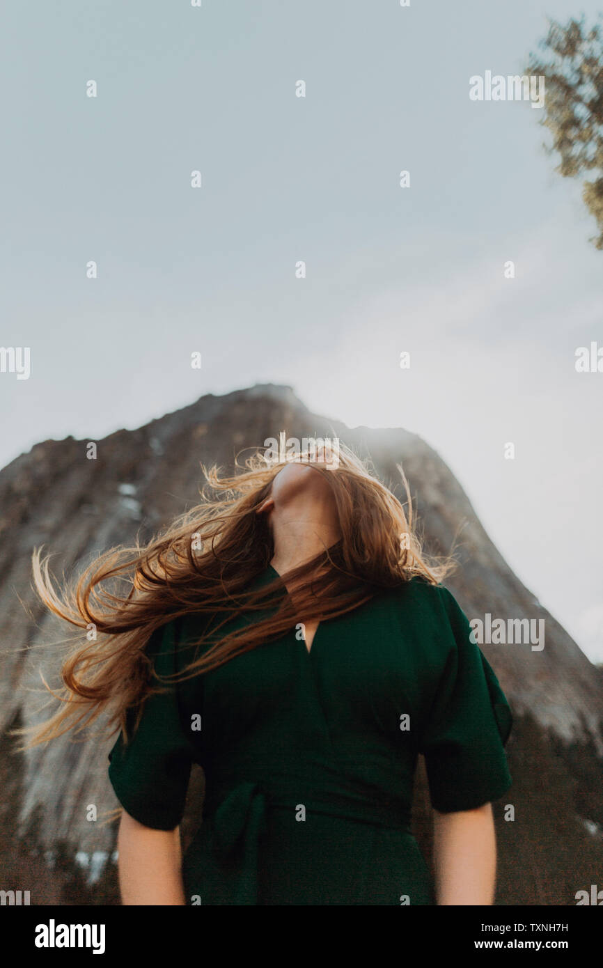 Junge Frau mit Flyaway Haar vor sonnenbestrahlten Berg, Yosemite Village, Kalifornien, USA Stockfoto