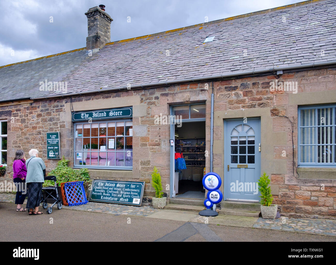 Zwei ältere Frauen Blick in Schaufenster eines Dorfes Laden namens der Insel Store ein General Store auf Lindisfarne heilige Insel Stockfoto