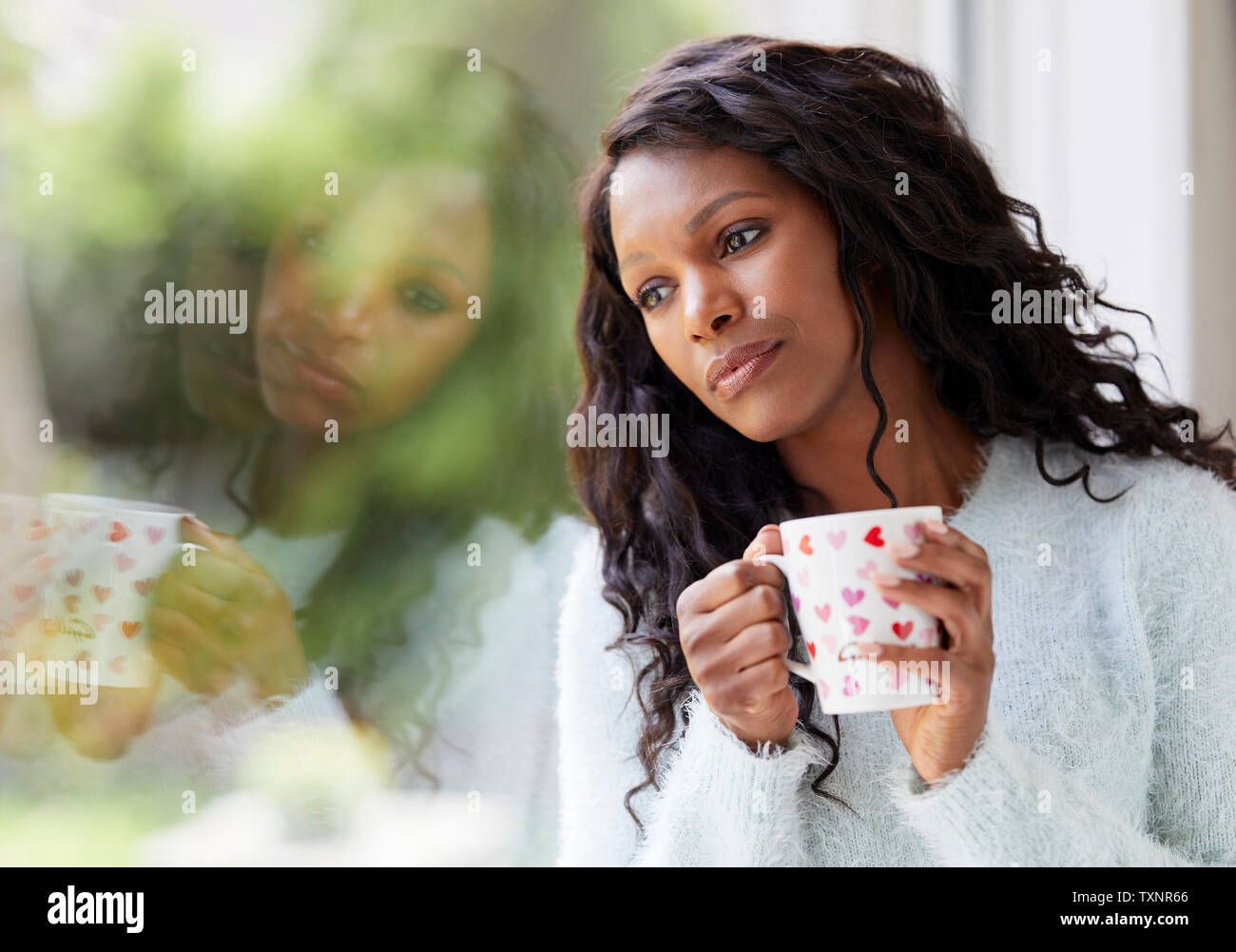 Ethnische Frau traurig saß in einem Fenster Stockfoto