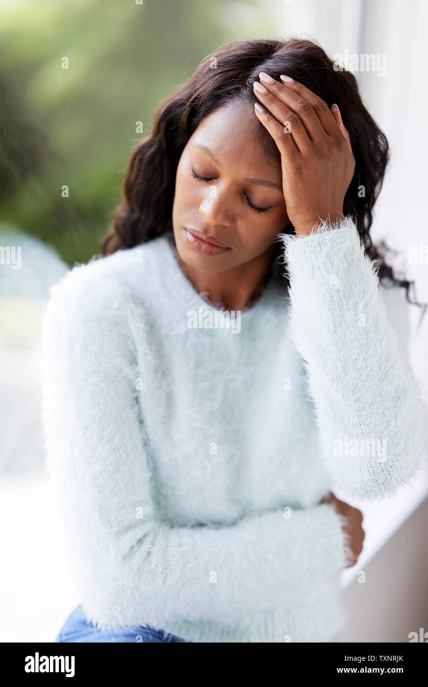 Ethnische Frau traurig saß in einem Fenster Stockfoto